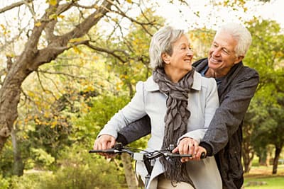 Retired couple riding bikes in a continuing care retirement community.