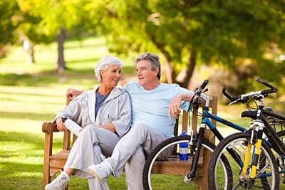 Retired couple siting on a bench in a park in a South Carolina continuing care retirement community.
