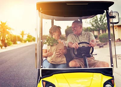 Retired couple riding in a golf cart in a Florida continuing care retirement community.